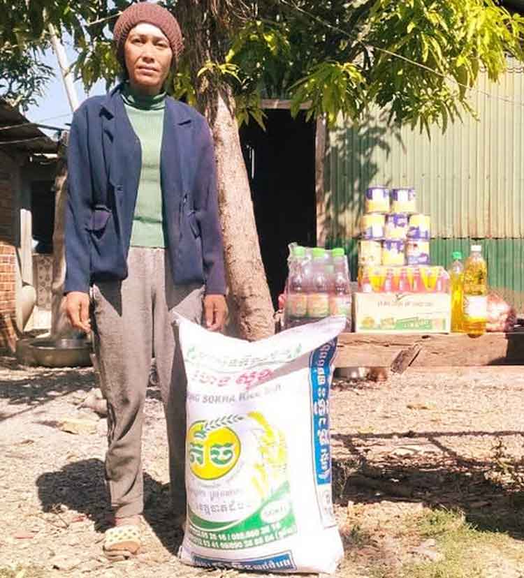 Vrouw met een zak rijst en voedselpakket voor haar huis in Cambodja
