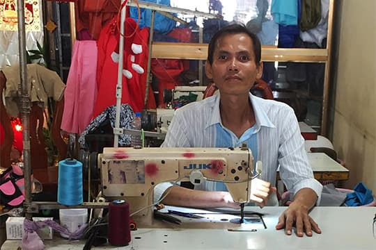 Man aan een naaimachine in een atelier
